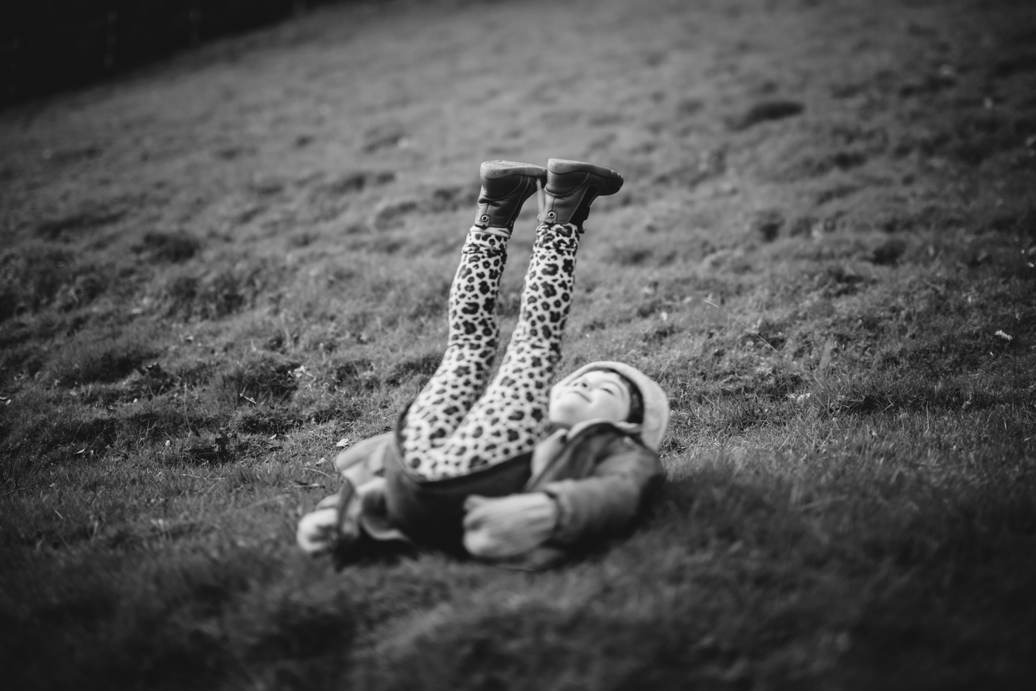 Copy of Black and white environmental portrait of a child lying on her b