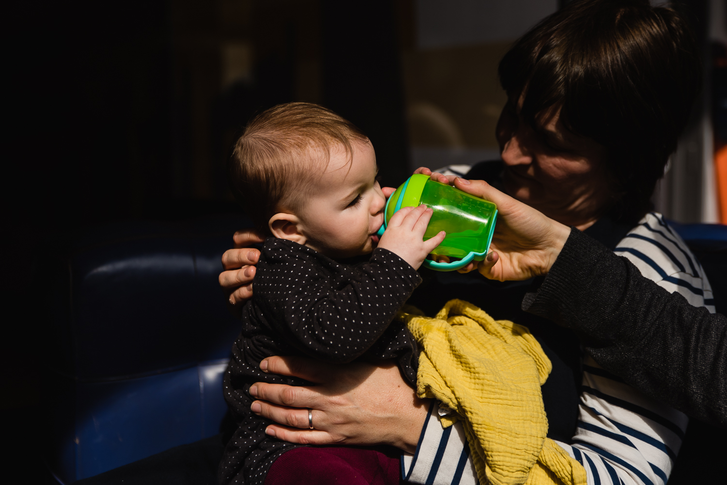 Baby drinks out of her green sippy cup on a family photoshoot in