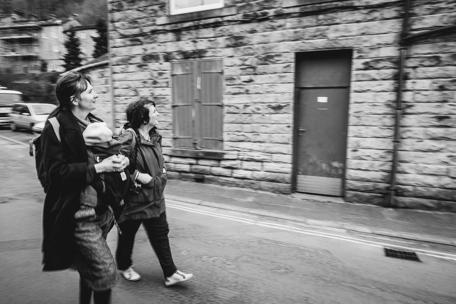 Black and white photography of a family walking past an old buil