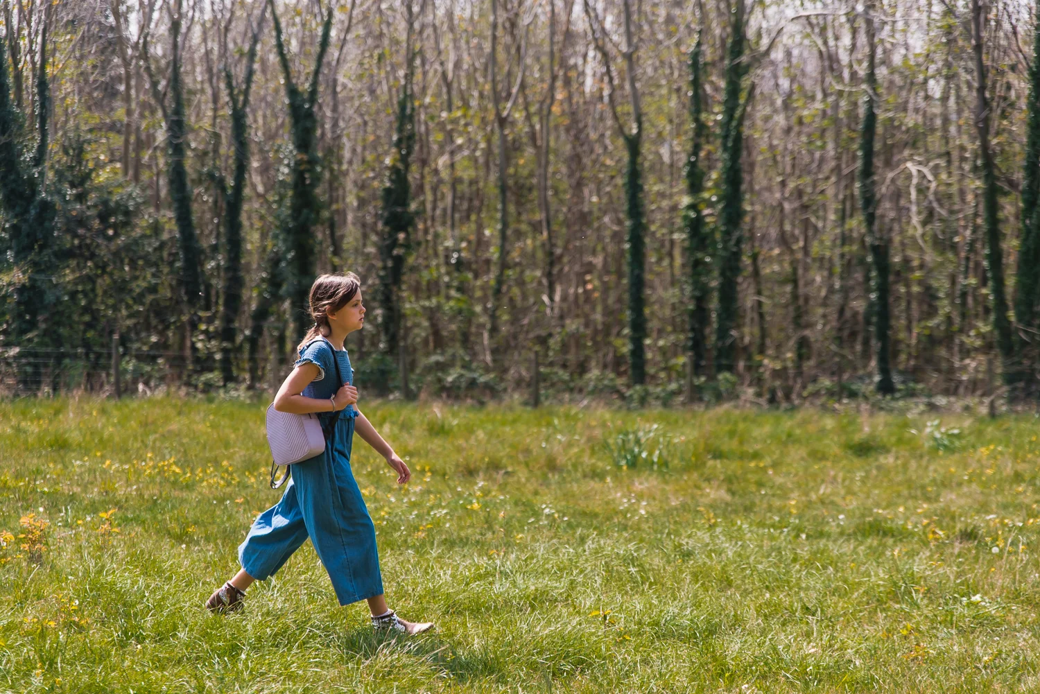 Girl carrying her pink rucksack walking across a field