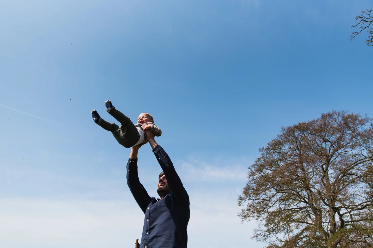 A father swinging his baby in the air on a family photoshoot with Diana Hagues Photography