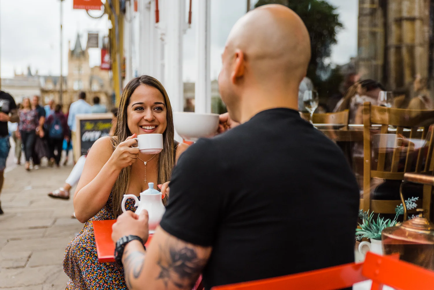 A woman drinks tea while smiling at her boyfriend during a couple photo session in Cambridge