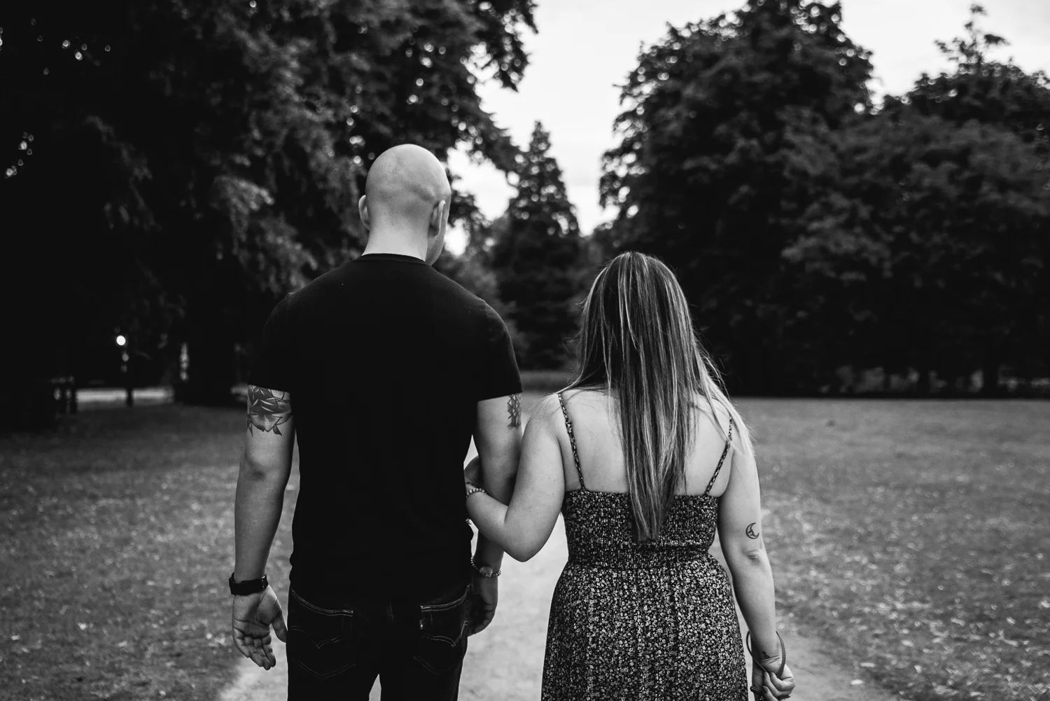 A couple walking away from the camera with the woman's arm linked around the guy during a couple engagement session in Cambridge