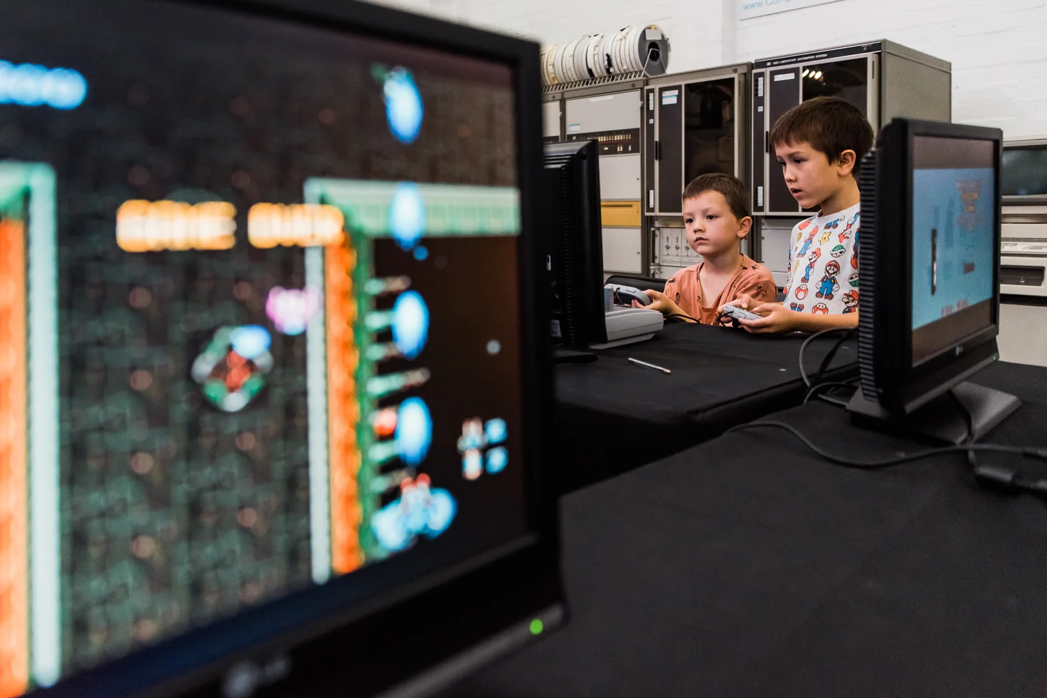 Two children playing computer games inside the Museum of Computing Science