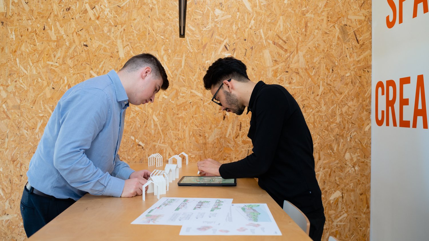  Two male architects discuss a plan together in an architect studio in Peterborough, Cambridgeshire, UK. 