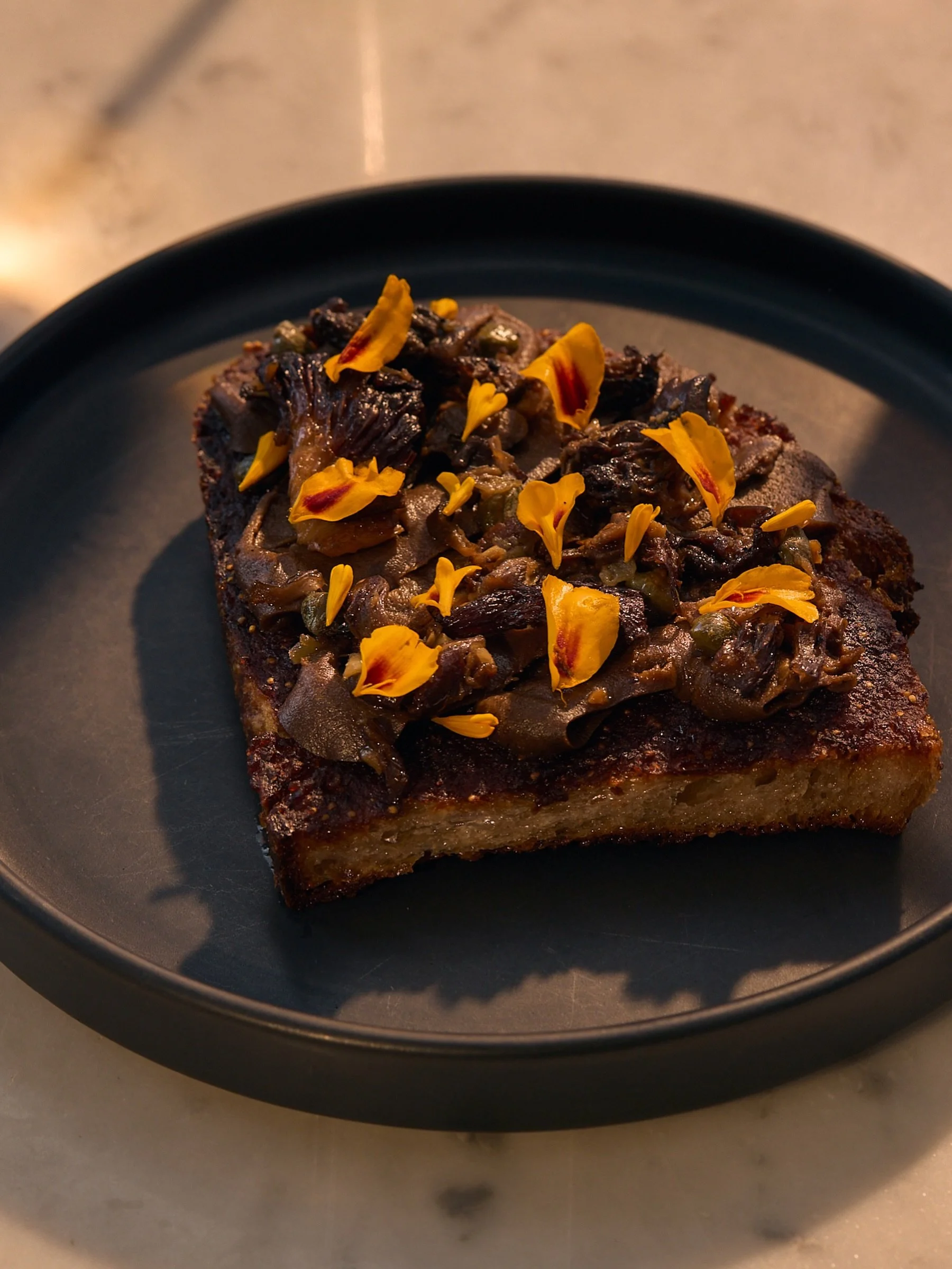 this season&rsquo;s toast is a perfect combo of rich, decadent, earthy, savory, sweet + crunchy. it all starts with our housemade sourdough, spread with fig jam, topped with a whipped vegan mushroom parfait + a wild mushroom conserva (think things pr