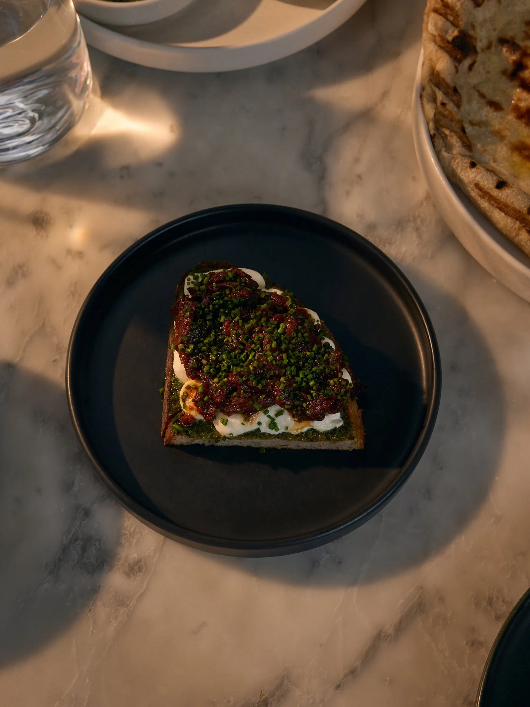 our seasonal toasts gets a summer update starting with a long confit of whole tomatoes, roasted low + slow in oil and aromatics until they are these jammy, umami packed, caramelized dark red gems that are set up on fresh, whipped ricotta + a tarragon