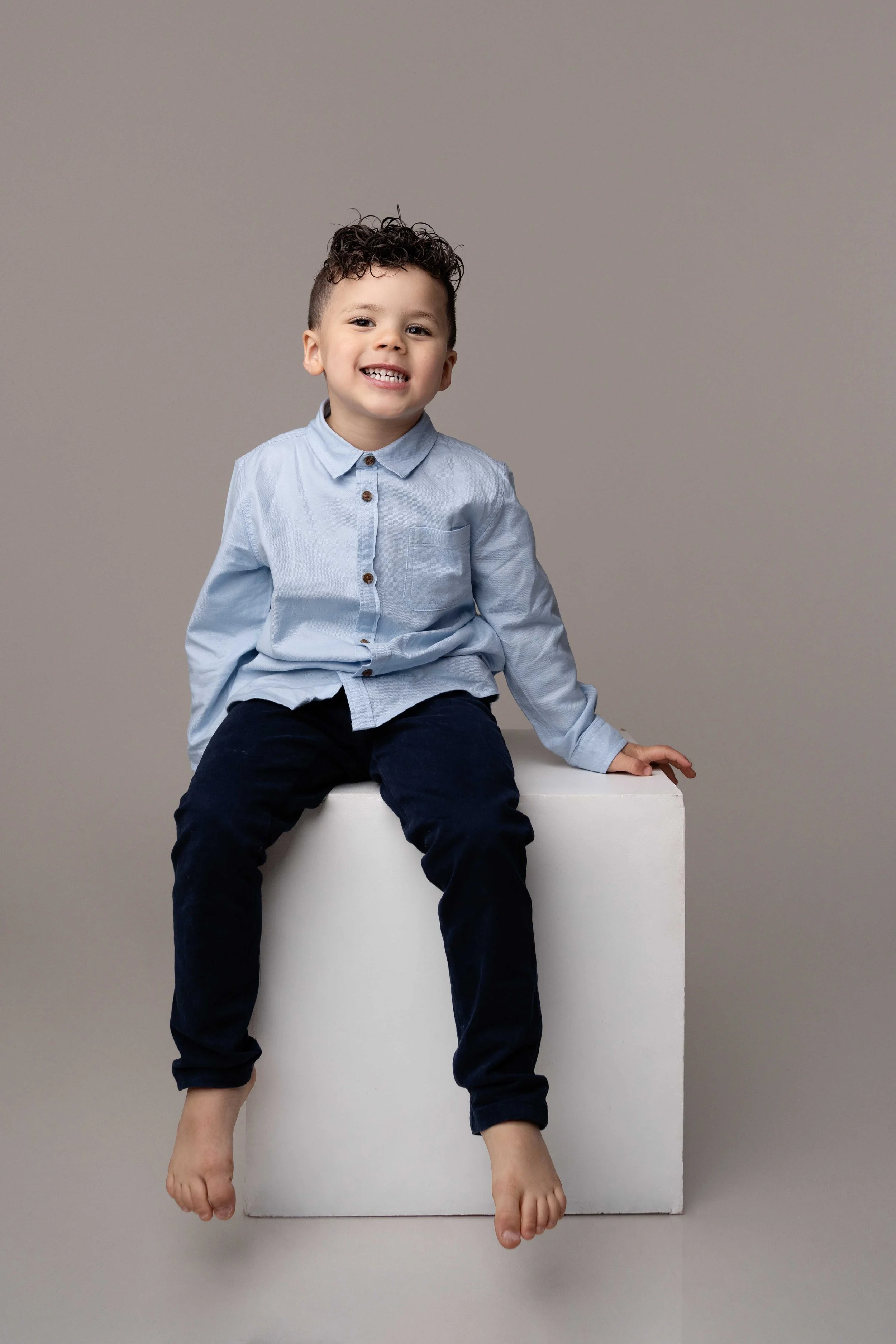 Child sitting on white box during portrait mini session at Lea Cooper Photography studio in Willenhall, West Midlands