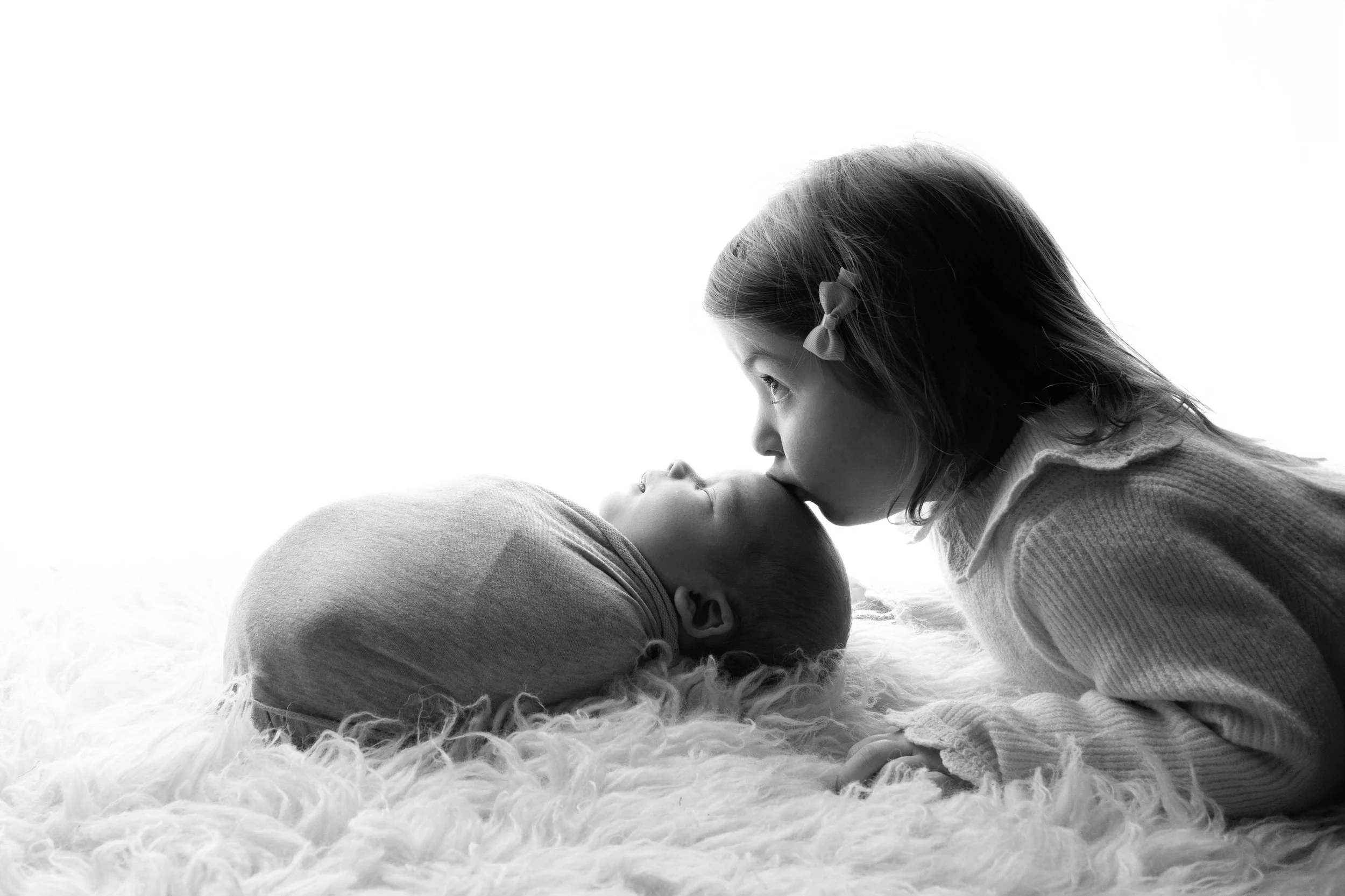 toddler kissing newborn during newborn photoshoot in wolverhampton, west midlands uk