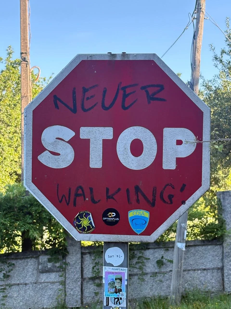 Graffitied stop sign on the Camino de Santiago, with NEVER written above STOP and WALKING! below.