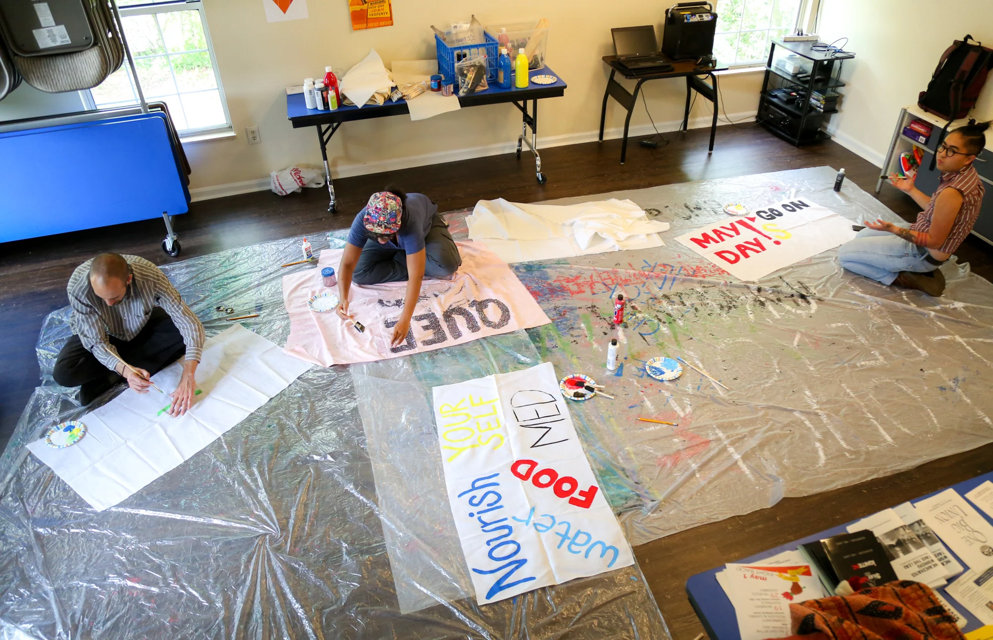 A couple of people show up painting the banners on the floor for May Day protest at the Southern Vision Alliance office in Durham on April. 22.