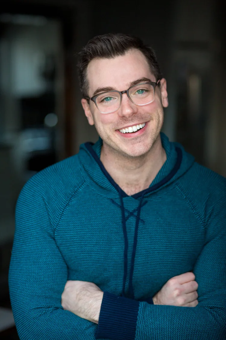 Trey smiling in glasses and a teal hoodie