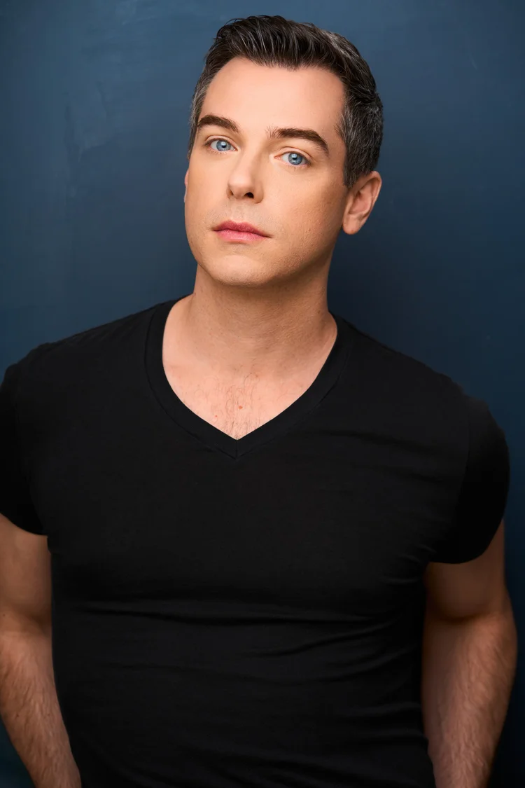 Trey in a black V-neck against a deep blue background