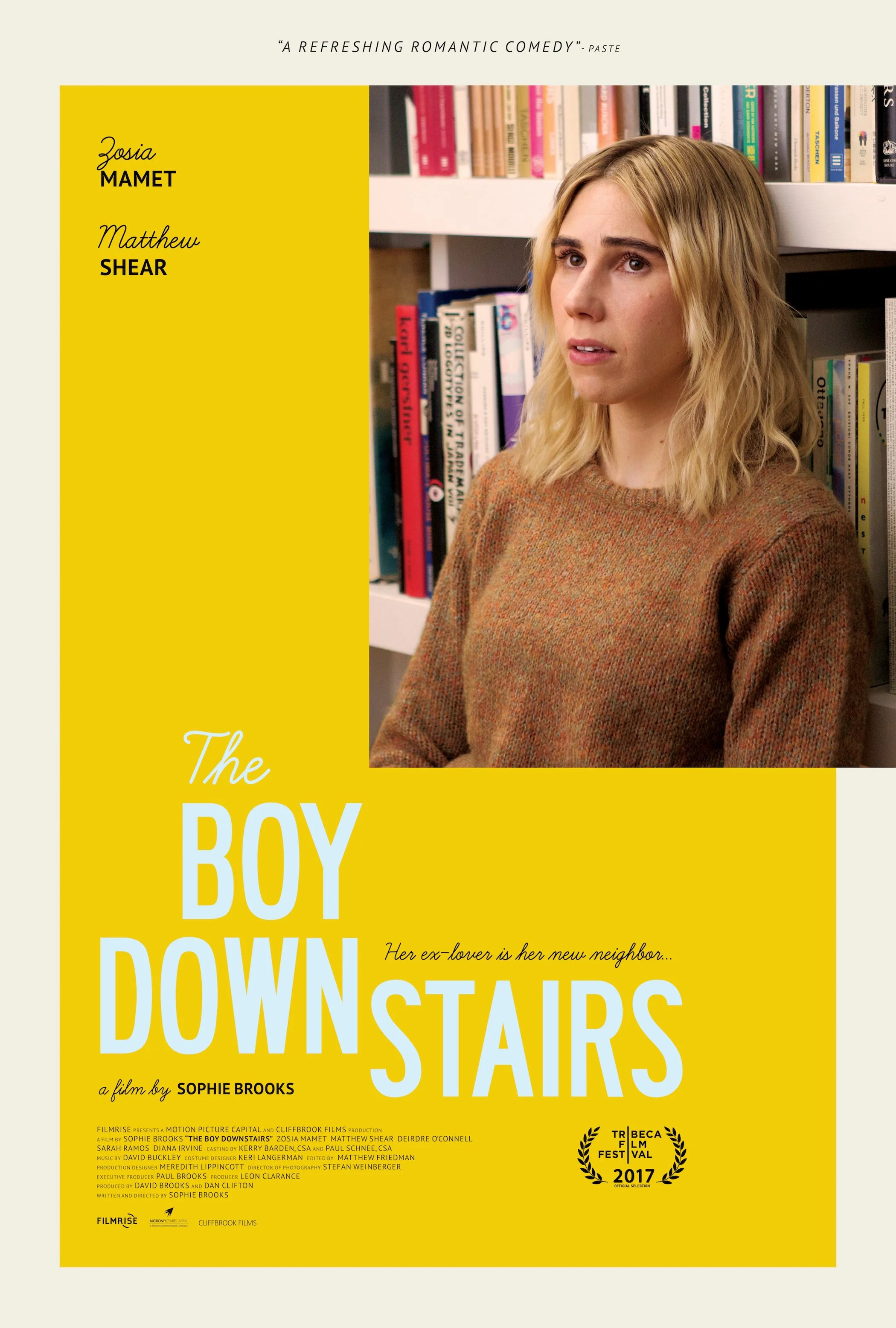 Movie poster for 'The Boy Downstairs' featuring a woman with blonde hair in front of a bookshelf, with the movie title in large white text on a yellow background.