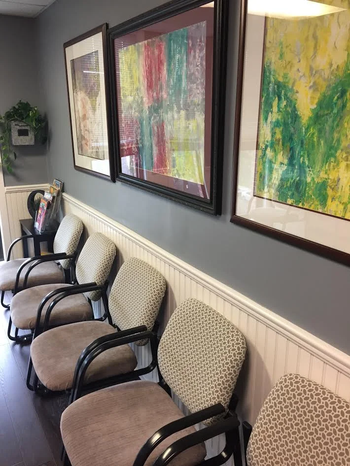 Waiting room chairs and abstract paintings against the wall.