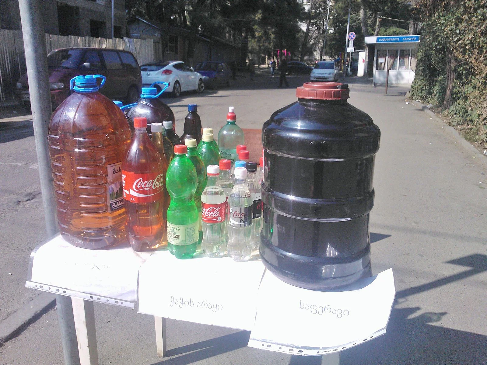 Home distilled chacha (in the middle bottles) and wine being sold in totally legit, not-at-all-dodgy bottles on the street in Tbilisi. Photo by Wikimedia Commons user Daniel-TBS.
