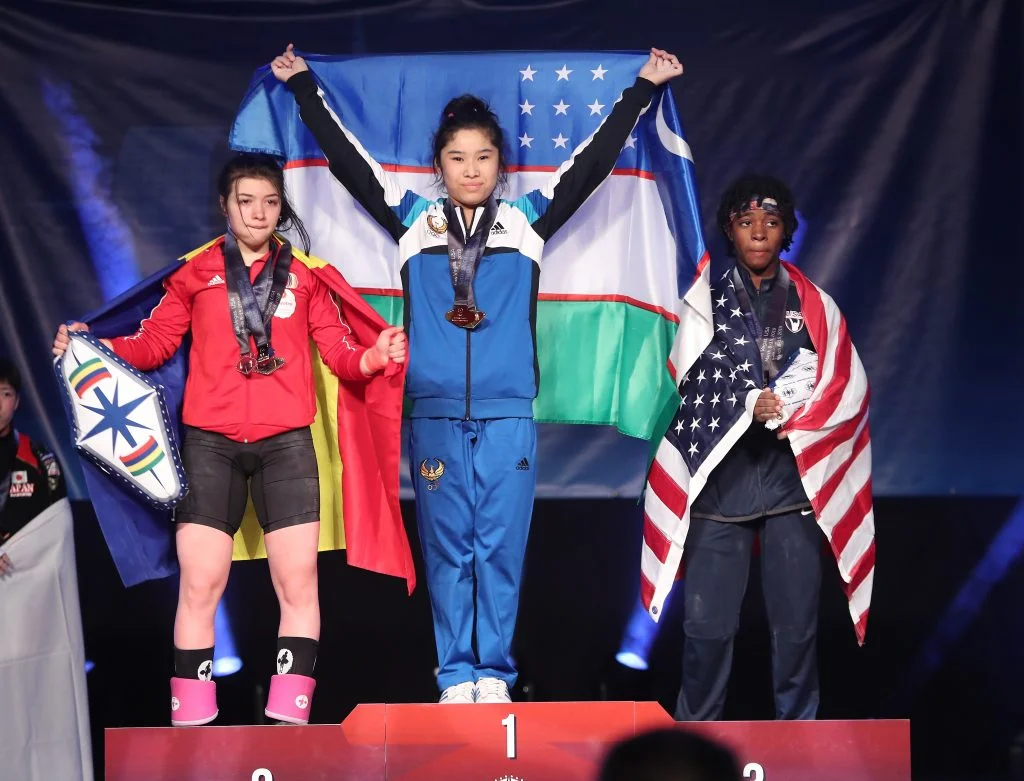Women’s 49-kilo medalists at the youth world weightlifting championships in Las Vegas, left to right — silver, Romania’s Mihaela Valentina Cambei; gold, Uzbekistan’s Nigora Abdullaeva; bronze, Kaiya Lashay Bryant of the United States // photo IWF