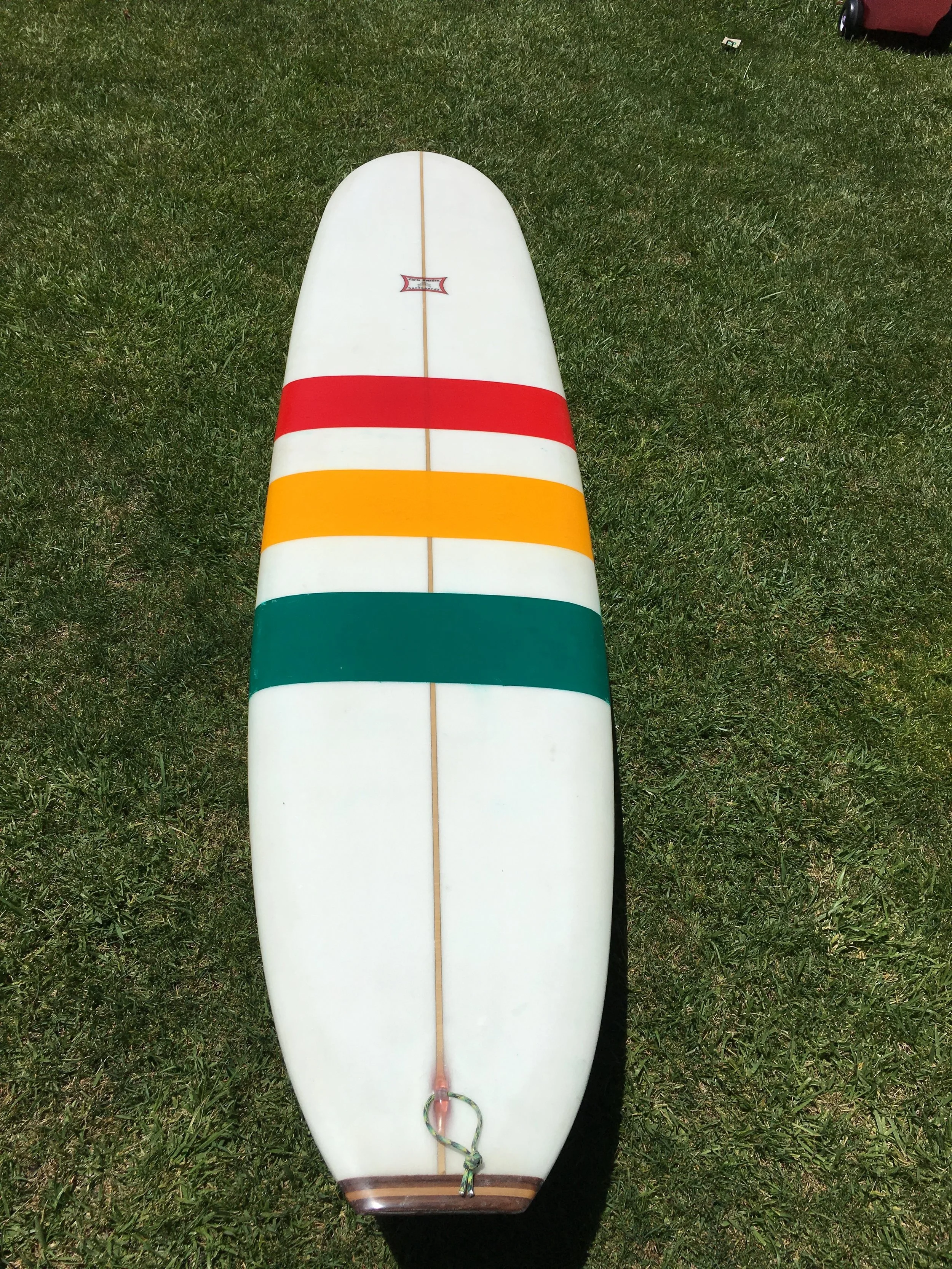  This was a 9'6" nose-rider made for Marcus. This board has 50/50 rails, a tail block made from walnut and birch with a matching wood fin. Marcus is from the old-school, and wanted simple rastafarian stripes and a classic look. A little less nose roc