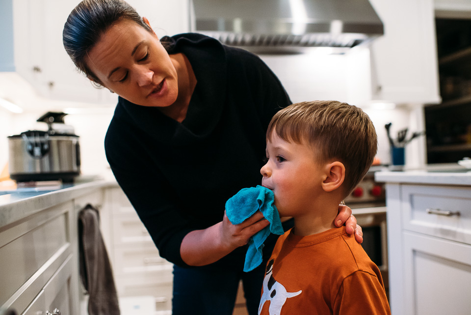 Mother cleaning a little boy's face with a cloth.