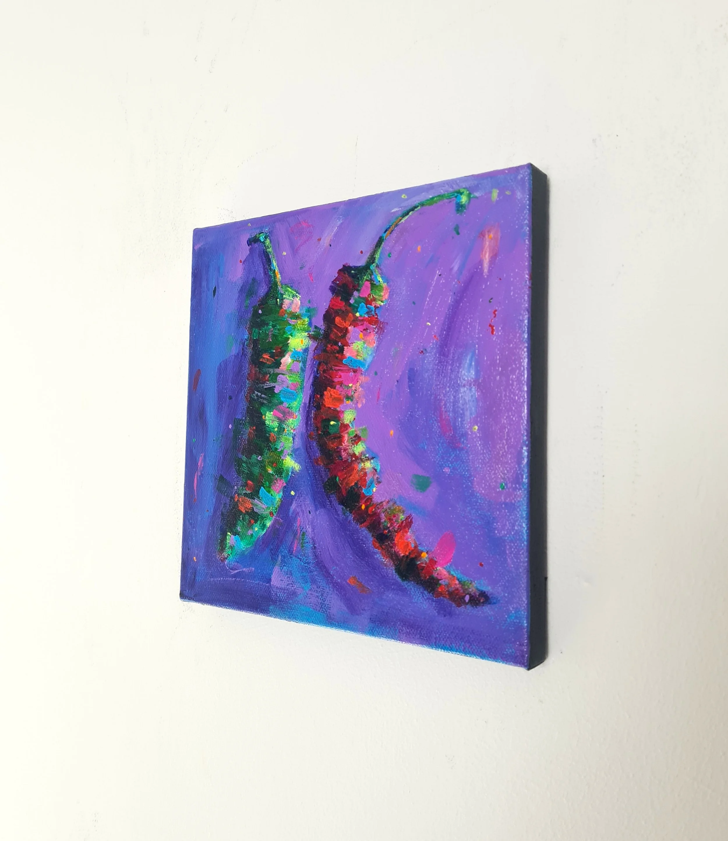 side view of a painting of two chilli peppers