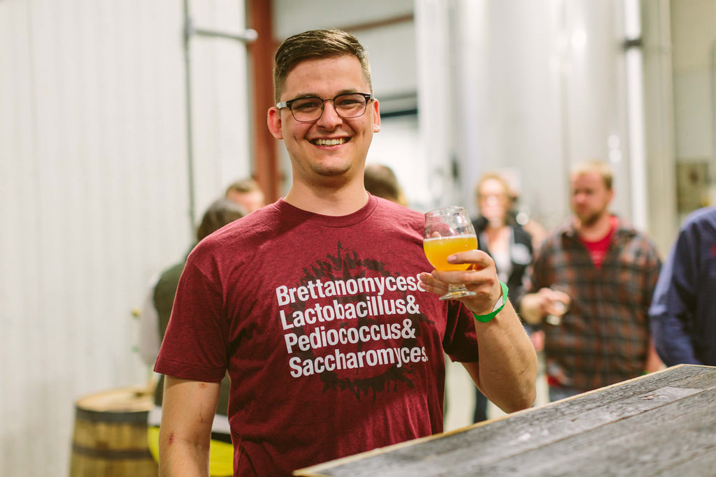 A beer enthusiast lists his microbial brewing partners on his shirt.