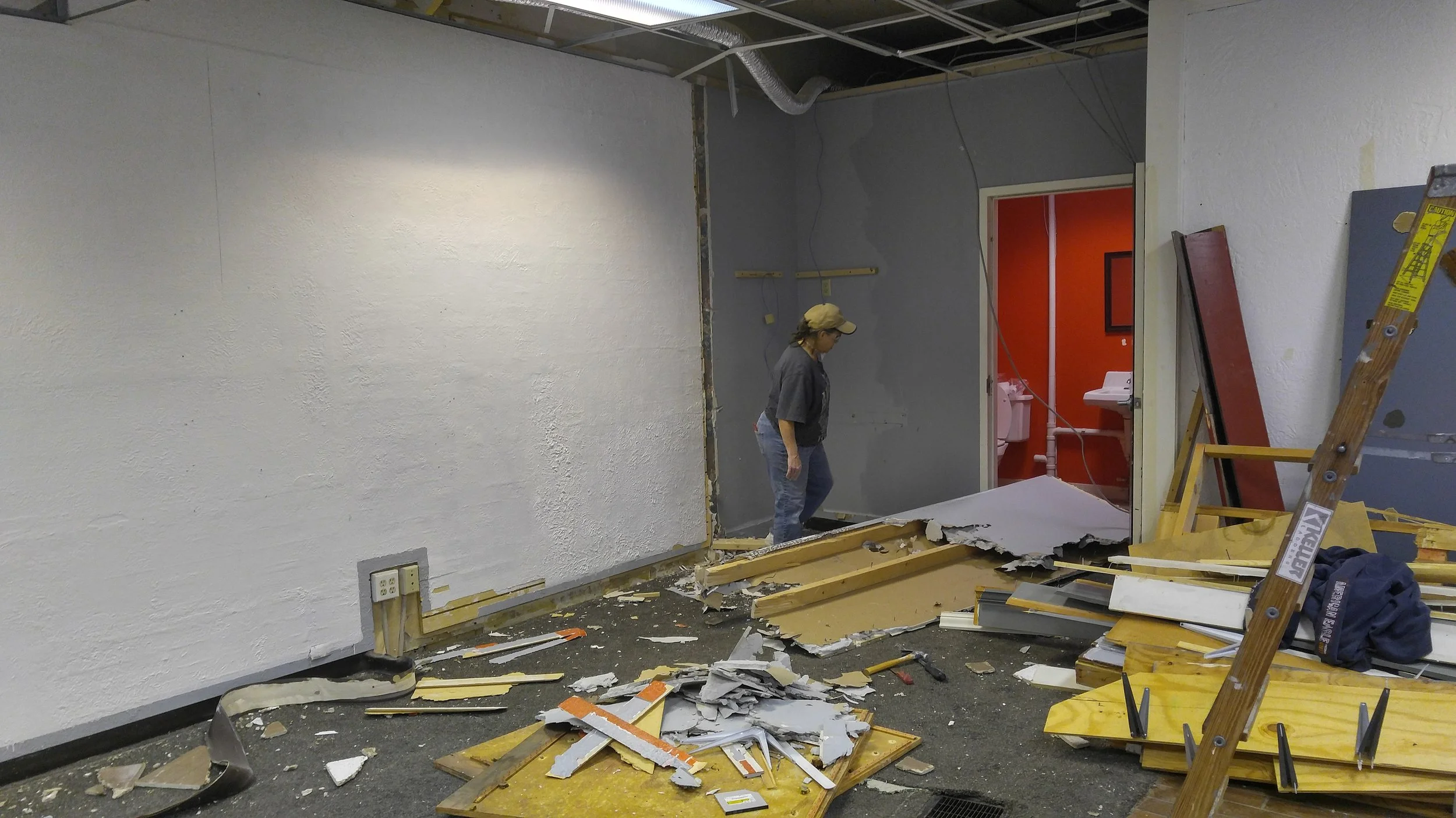 Tearing down a partial wall in order to improve flow of foot traffic to the restroom.