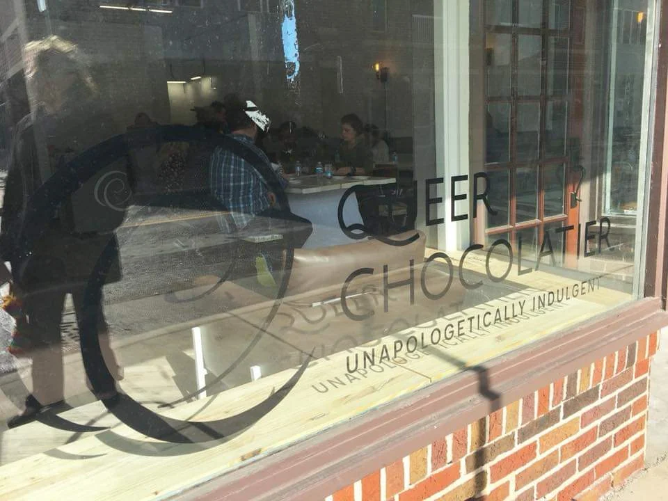 Queer Chocolatier Chocolate House at 1624 W. University Avenue in Muncie, Indiana. Window sign designed and installed by members of Studio 165+.