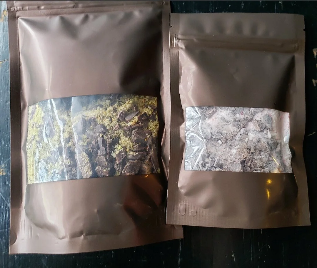 Two brown ziptop pouches side-by-side containing drinking chocolate kit ingredients