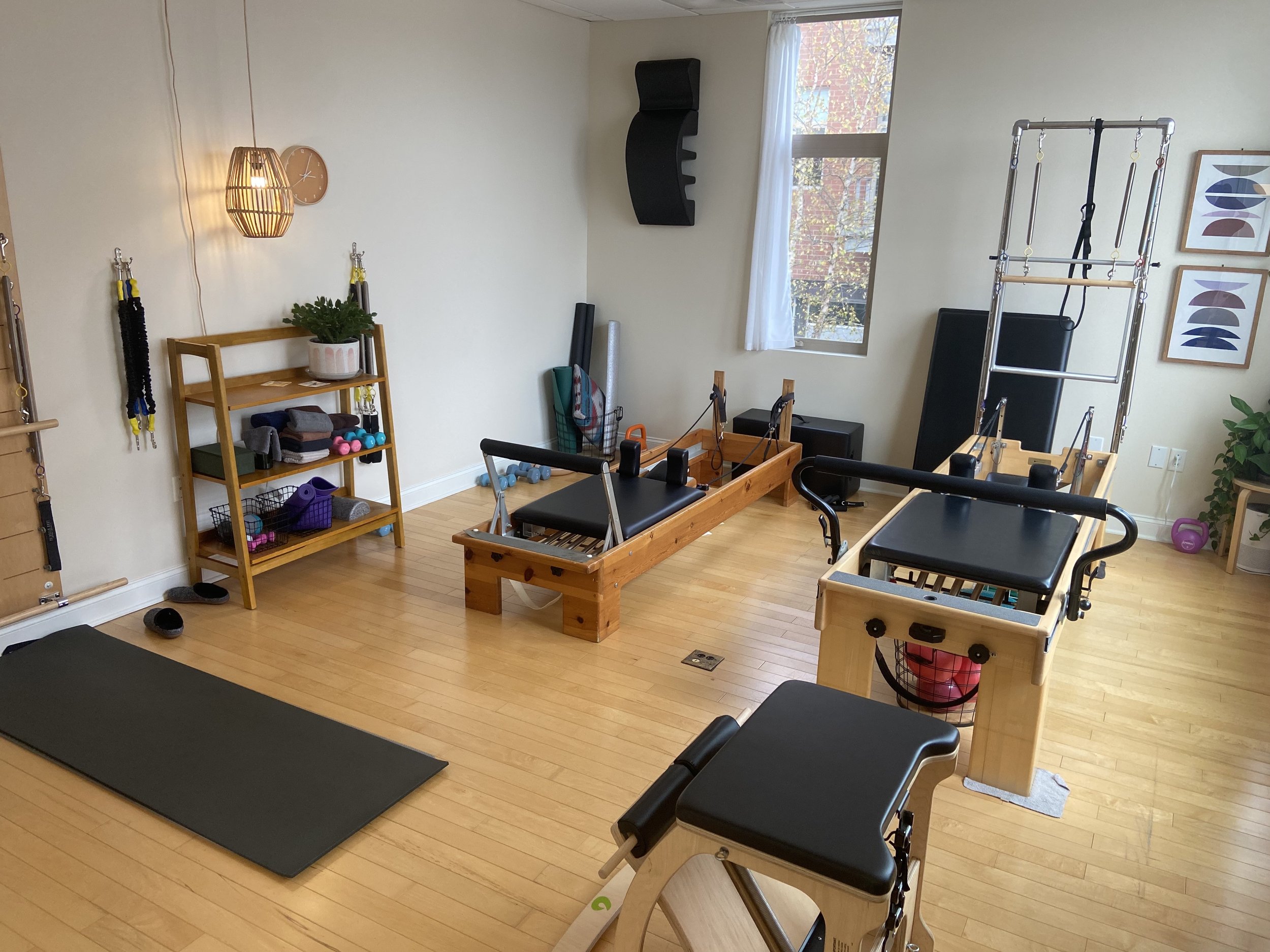 Image of cozy Pilates studio with 2 Pilates reformers and other movement props.