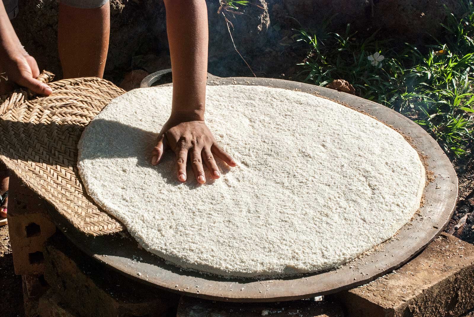  It is then sprinkled onto a hot stone above an open fire and packed down and cooked to make cassava bread (known as  beiju  in Brazil).  Photo © Tina Leme Scott  