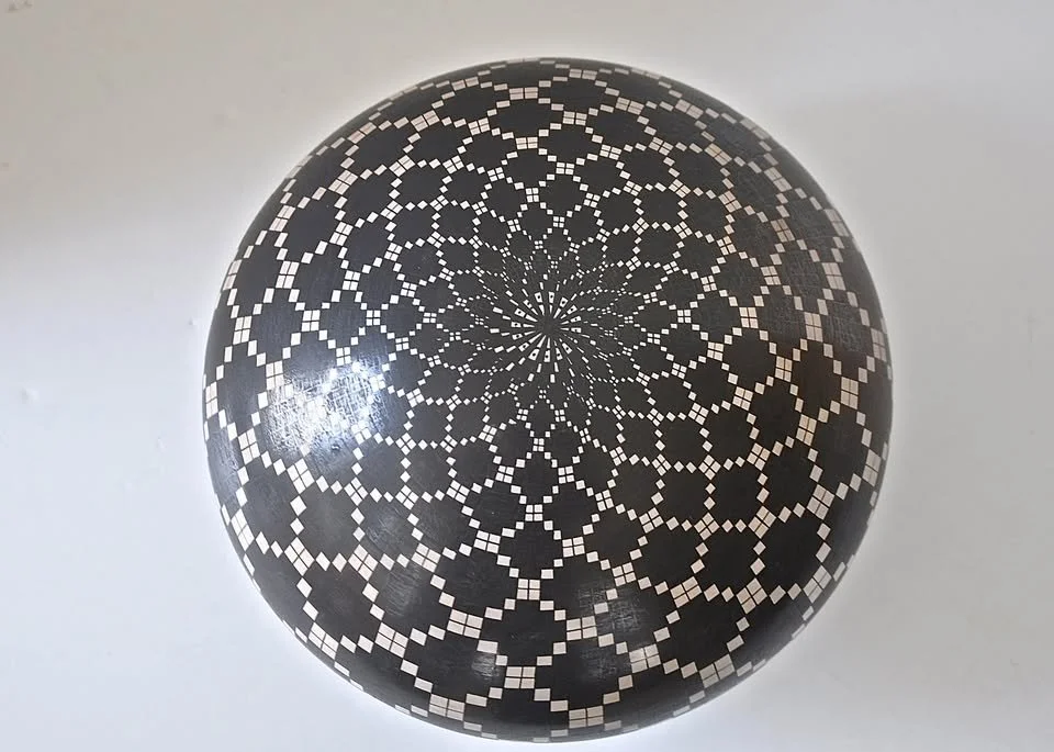 Bottom view of Juan Quezada black-on-white geometric olla, showing intricate radiating starburst pattern.