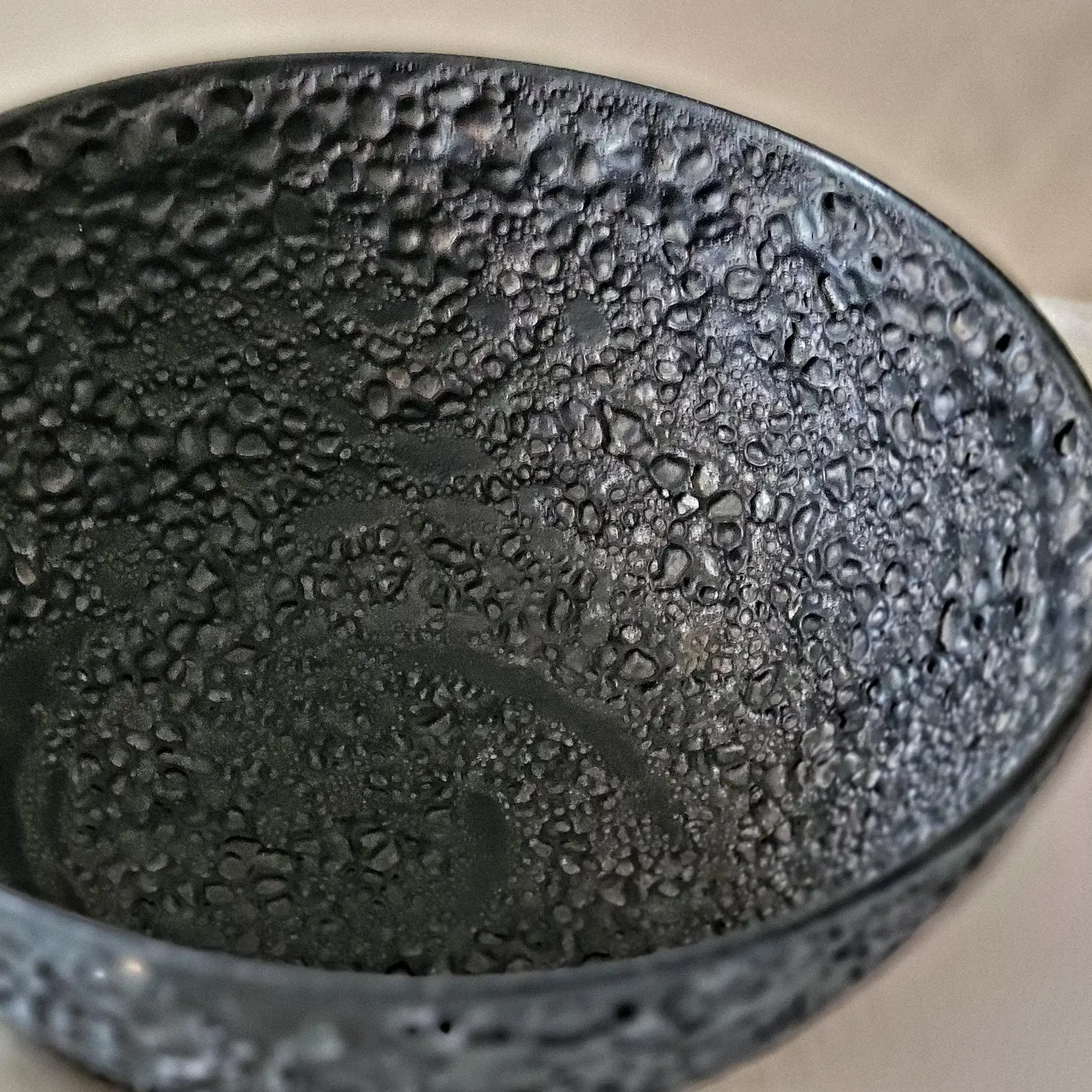 Close-up detail of Black Lava glaze showing raised cratered volcanic texture.