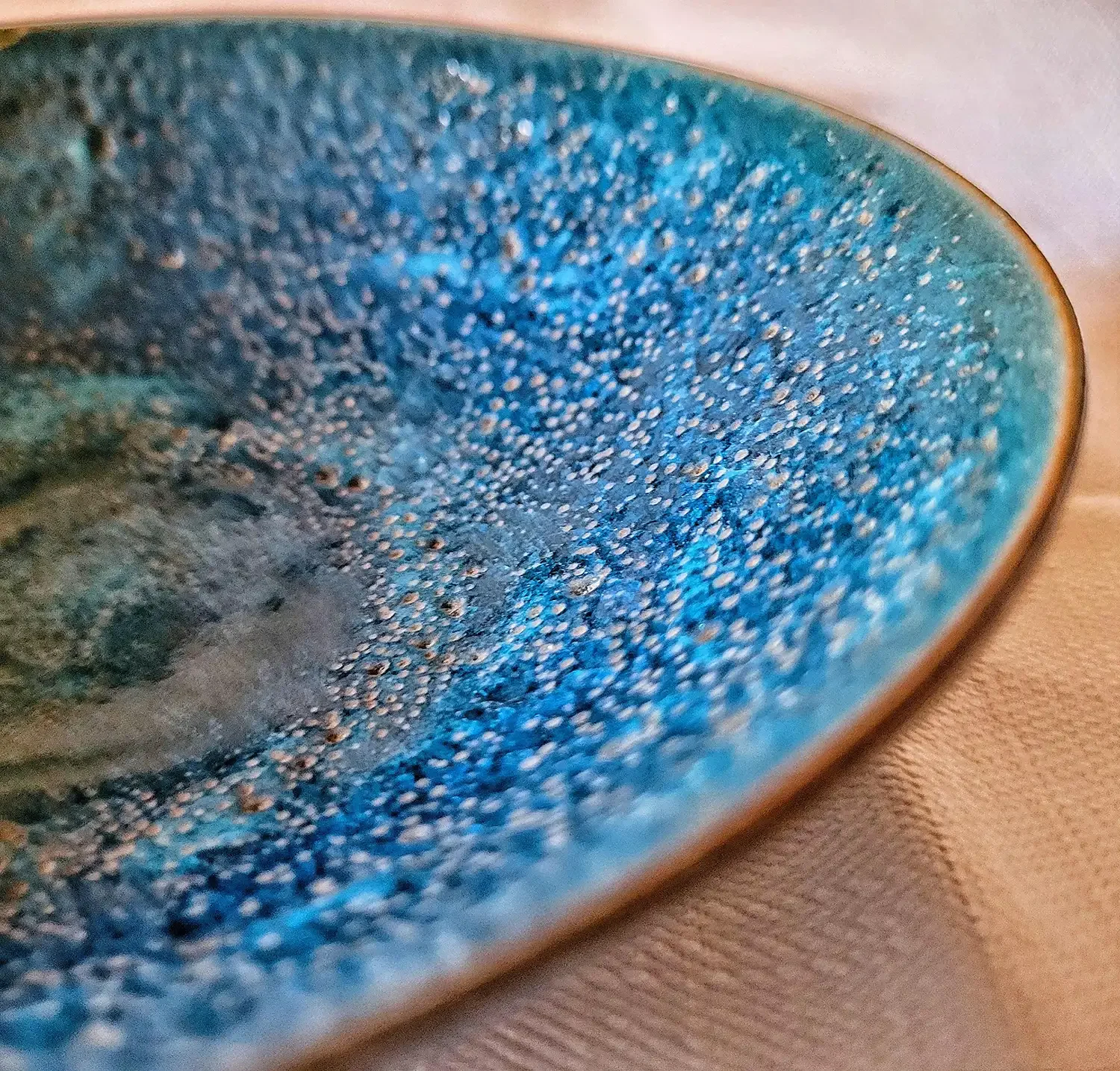 Angled detail of Natzler Prussian green–blue bowl showing fine crater texture along the rim.