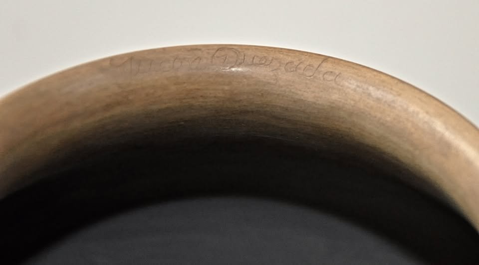 Close-up of Juan Quezada signature incised on the rim of a black-on-white geometric Mata Ortiz olla.