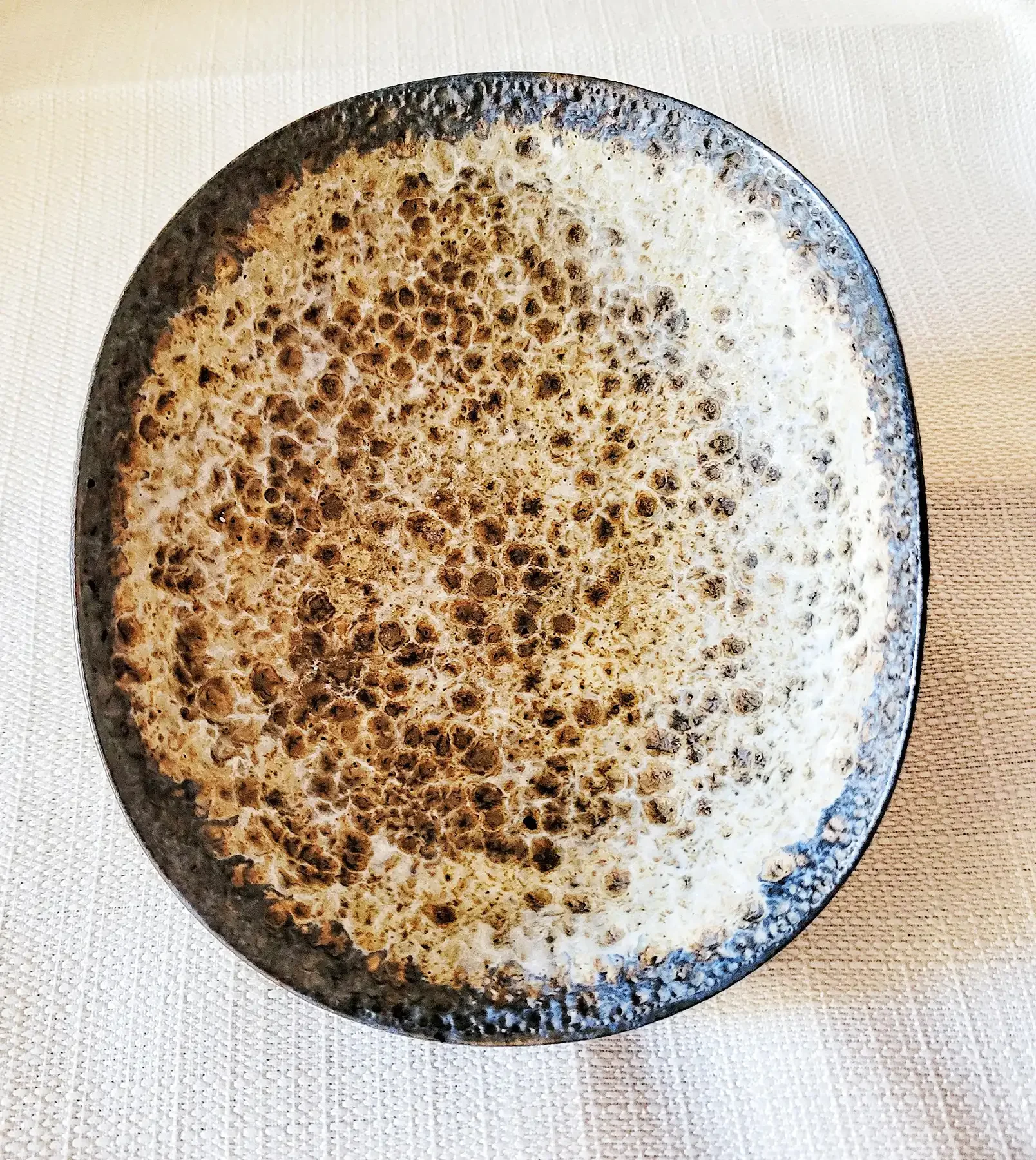 Top view of Natzler bowl featuring dense foamed white-lava glaze pattern in cream and brown tones.