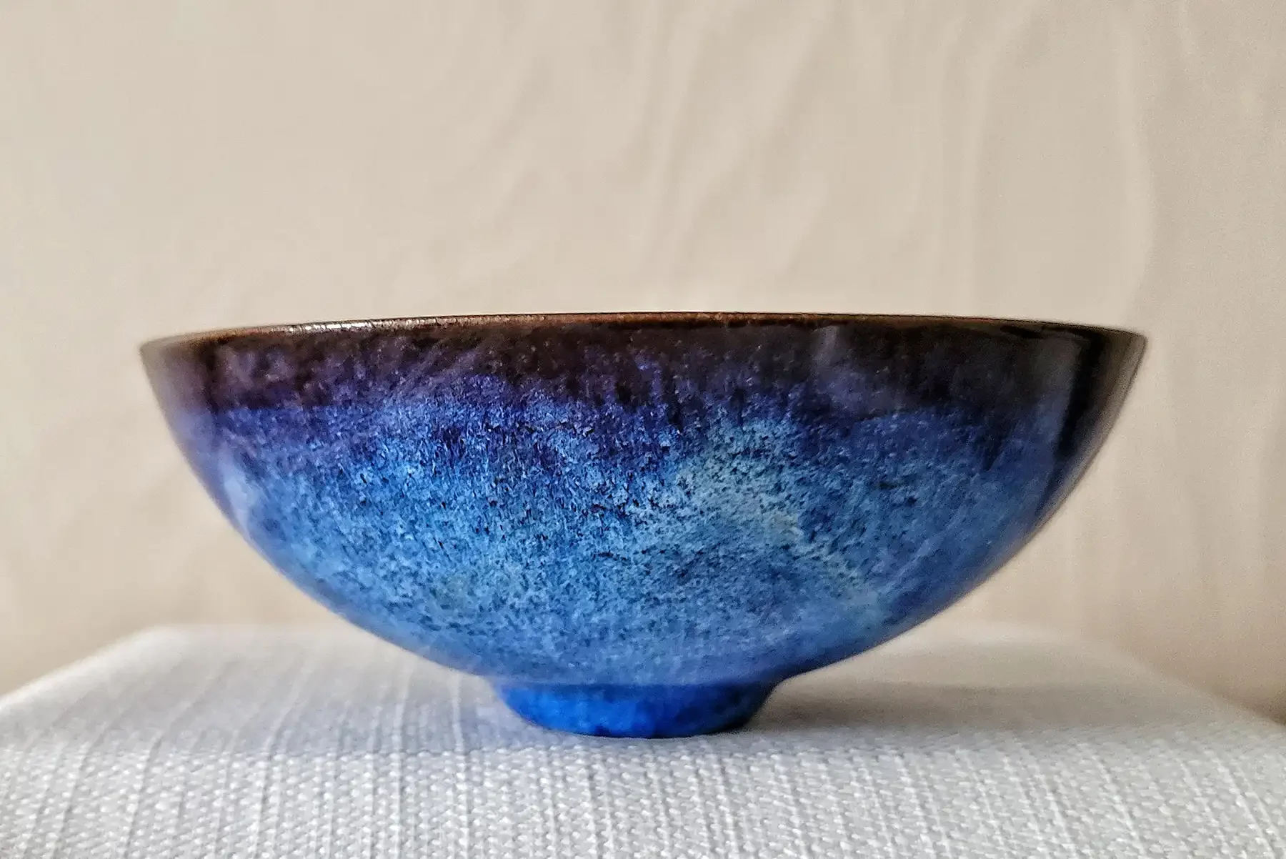 Side view of a Gertrud and Otto Natzler earthenware bowl with Blue Hare’s Fur glaze, transitioning from deep cobalt at the rim to lighter blue near the foot.