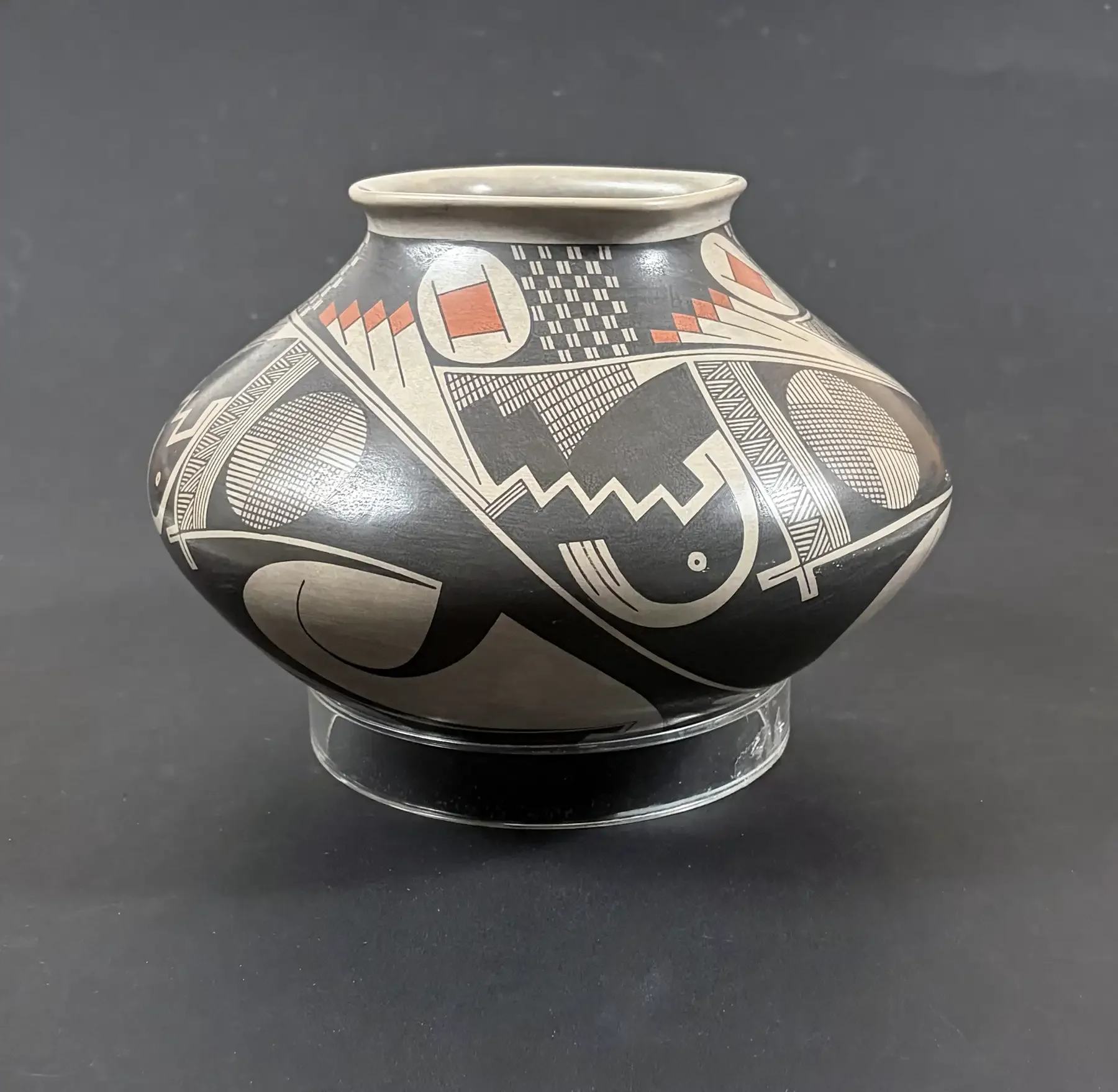 Polychrome Mata Ortiz geometric olla by Juan Quezada, featuring black, cream, and red painted designs on a rounded, stone-burnished vessel.