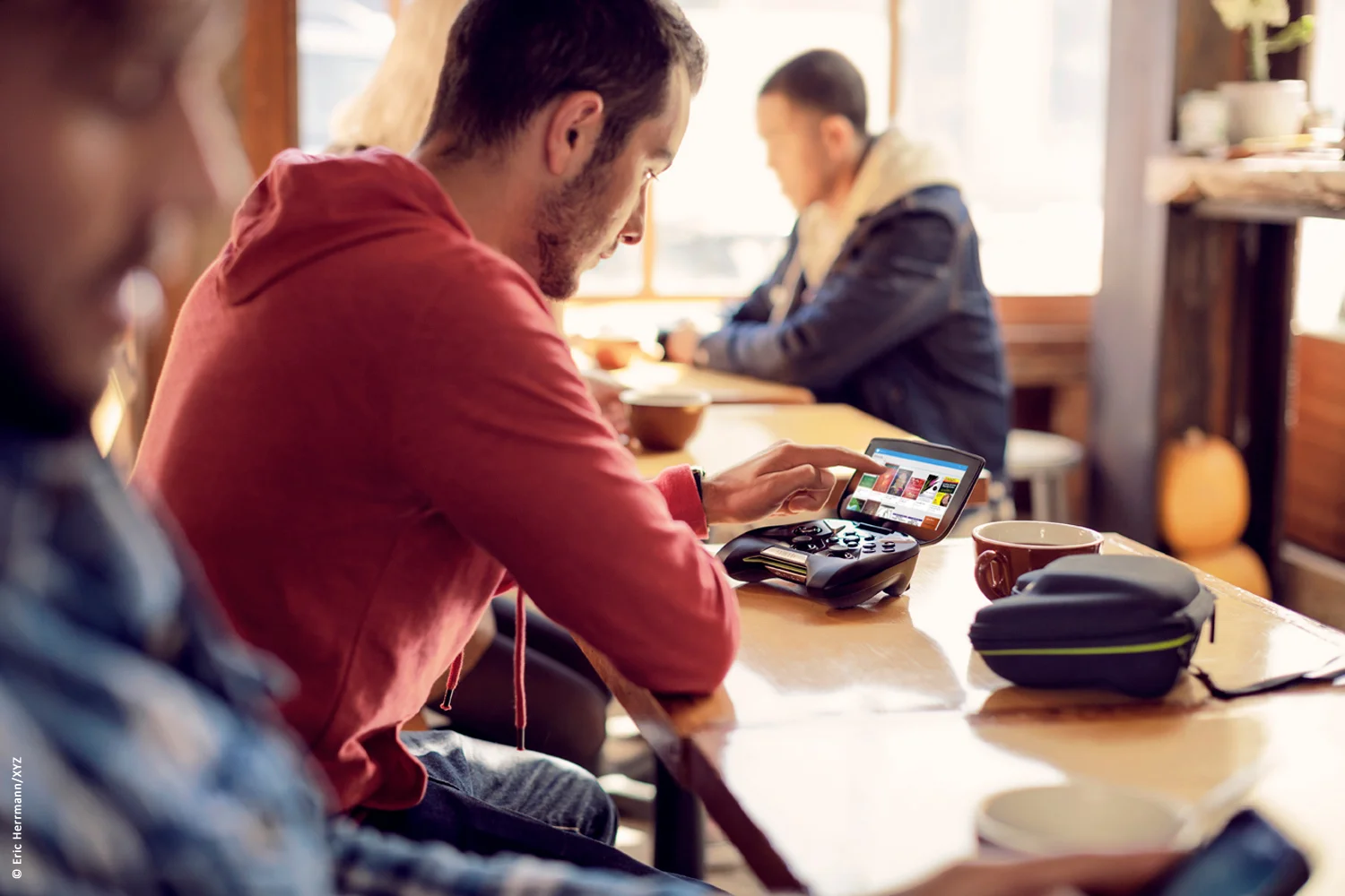 photo of three young men at sunny coffee shop one is looking at the screen of his Nvidia Shield device
