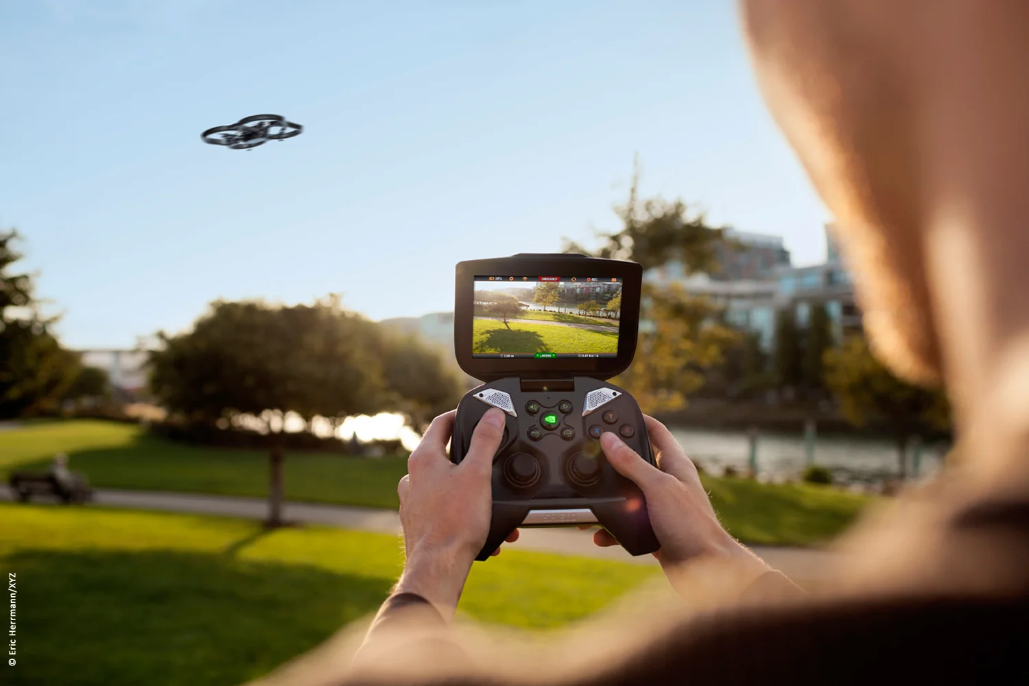 close up photo of a male model at a park location operating with his Nvidia Shield device to fly a drone