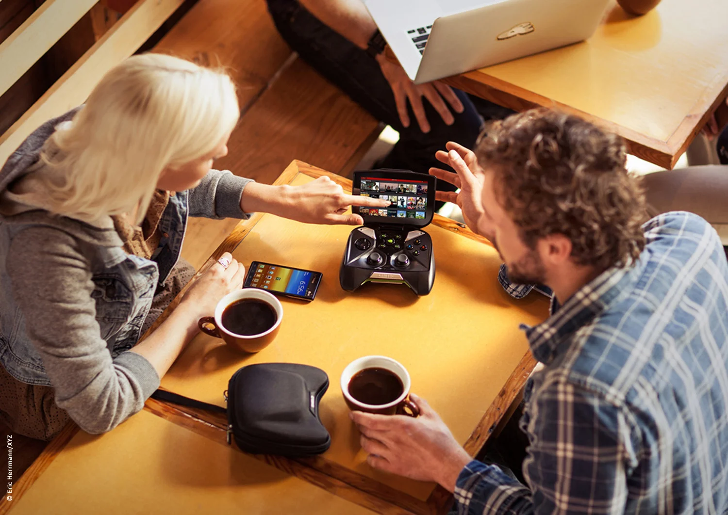photo of a man and woman drinking coffee at a cafe viewing images streaming on the screen of a nvidia shield