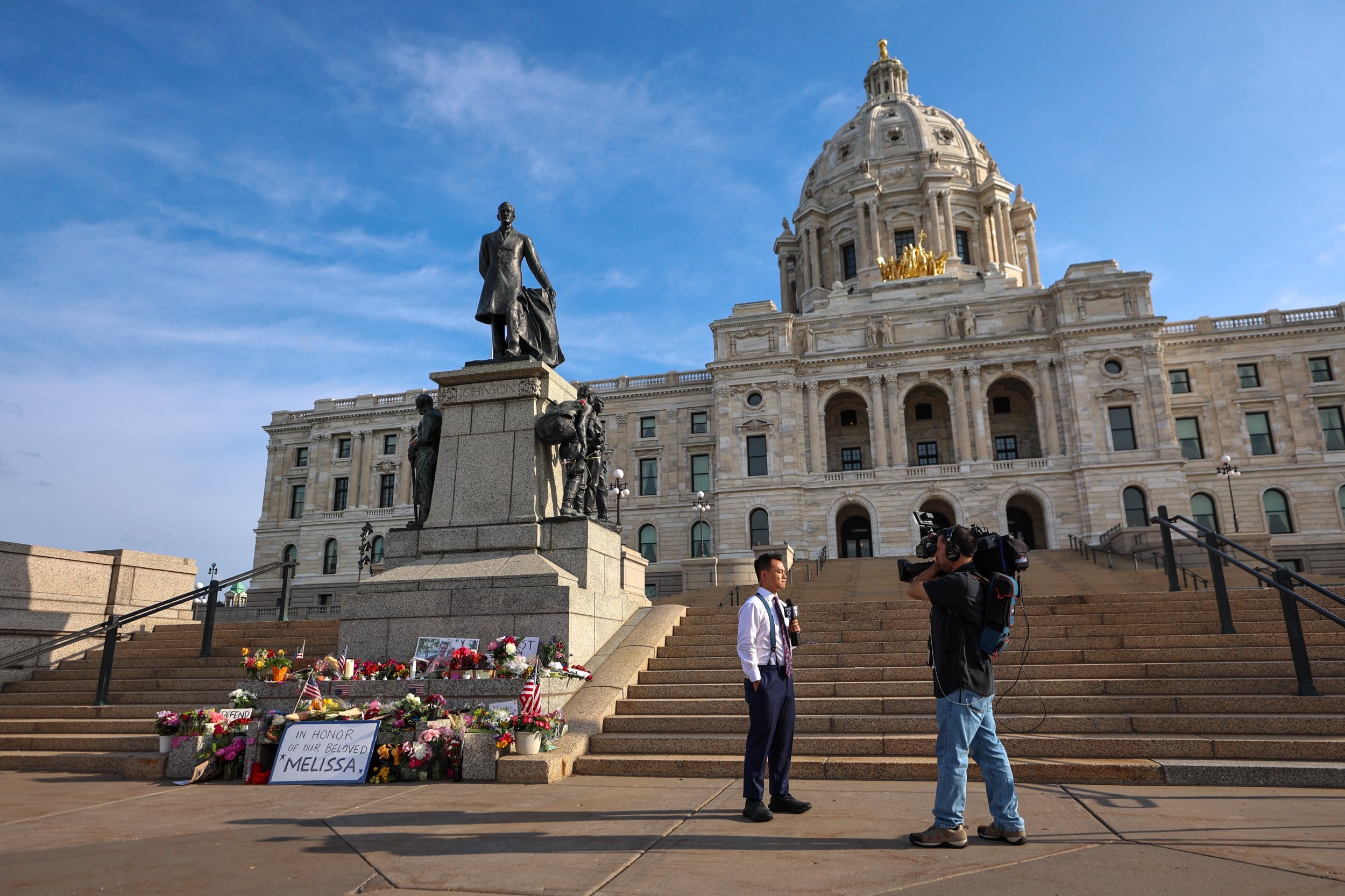 ST PAUL, MINNESOTA - JUNE 16: A local television crew reports next to a makeshift memorial for DFL State Rep. Melissa Hortman and her husband Mark Hortman is seen at the Minnesota State Capitol building on June 16, 2025 in St. Paul, Minnesota. (Stev