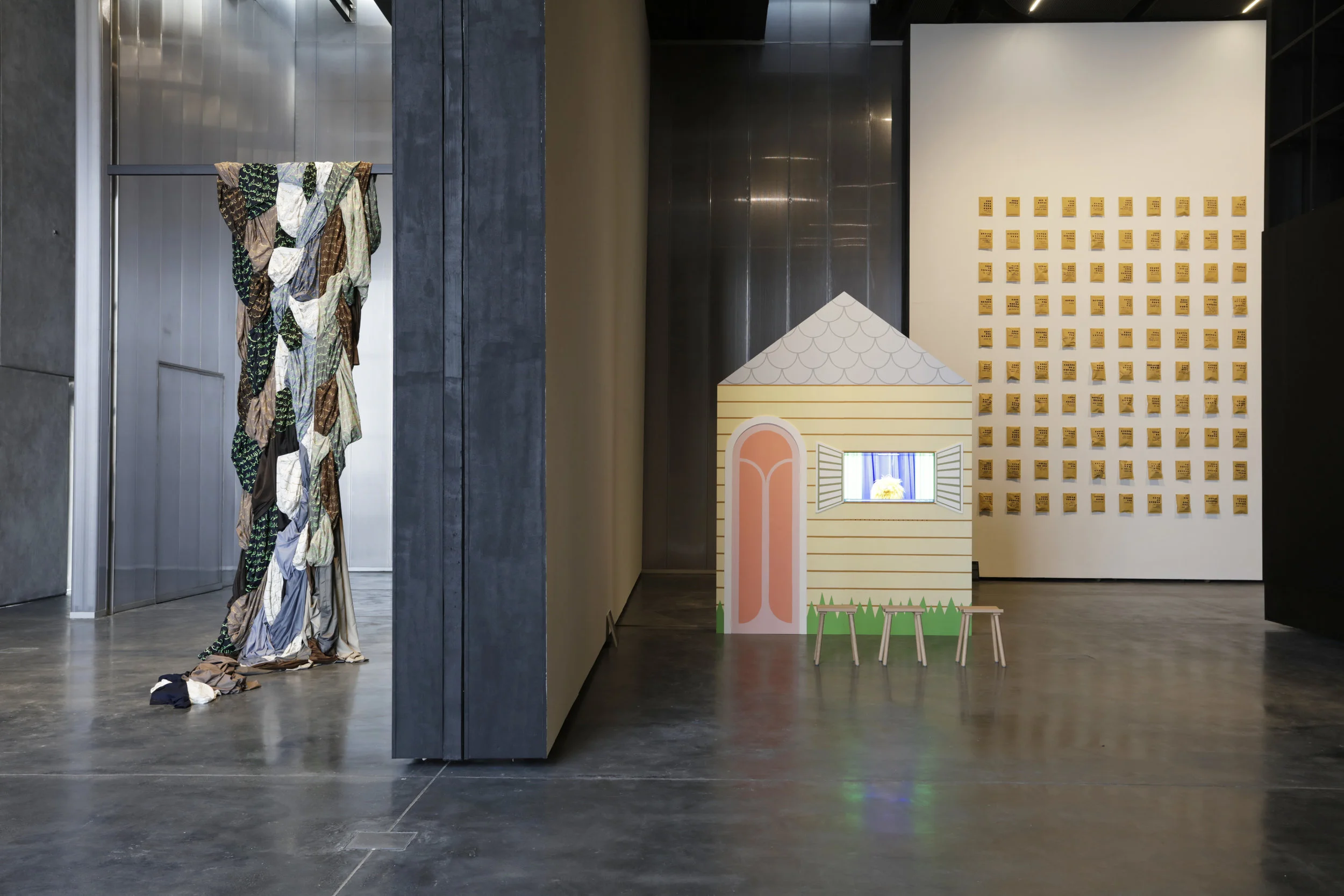Ishara: Signs, Symbols and Shared Languages (installation view). Hanging on the left is Amna Al Dabbagh’s The Hanging Odes (2018) and the installation on the right is Farah Al Qasimi's Everybody was Invited to a Party (2018) . On the rear wall is Nasir Nasrallah's Forgotten Title (2018) made of 100 everyday objects in envelopes with a coded description written on the surface. Courtesy UAE Unlimited and Alserkal Programming.