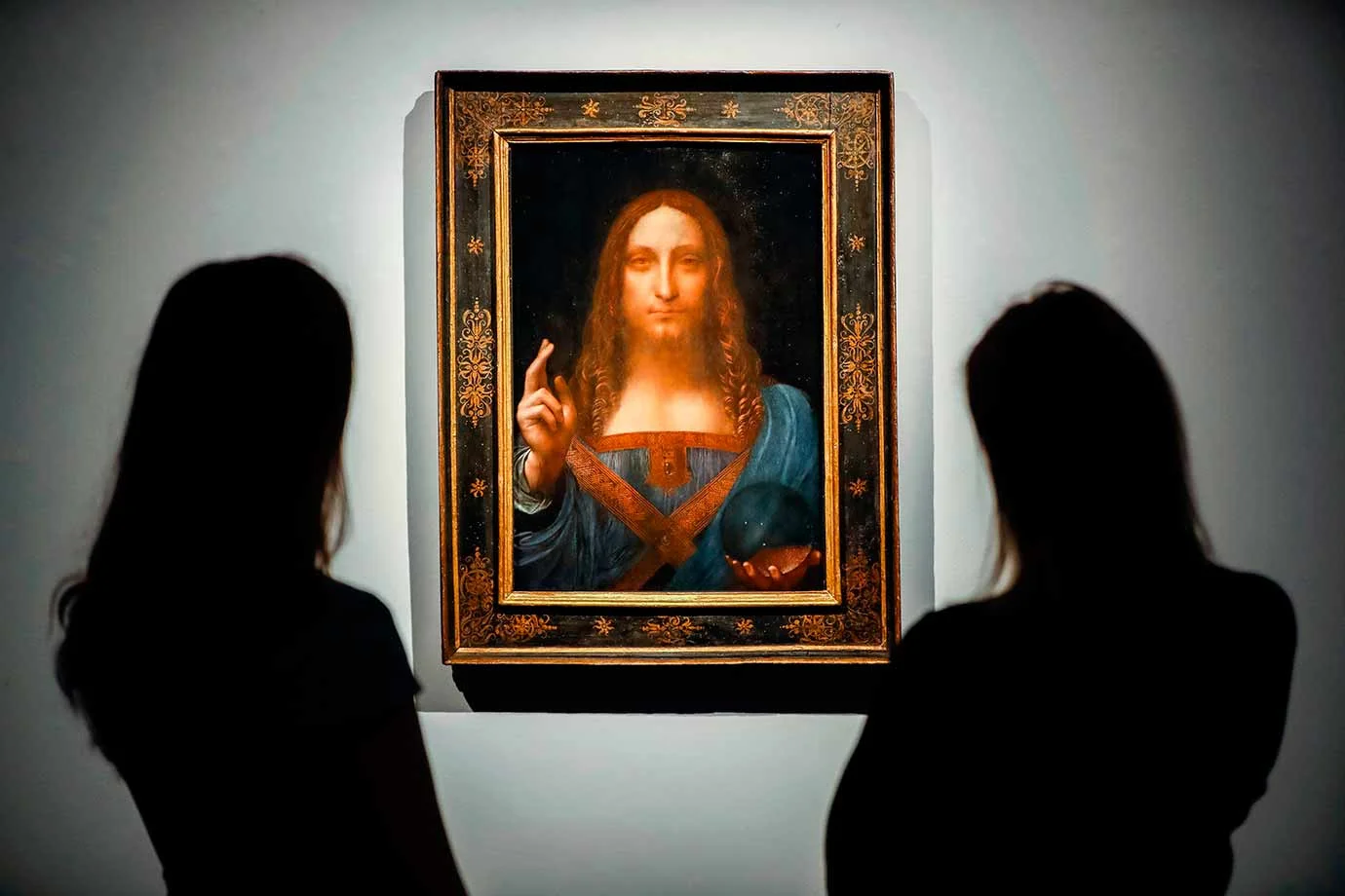 Christie's employees pose in front of Salvator Mundi by Leonardo da Vinci. Image Credit:AFP