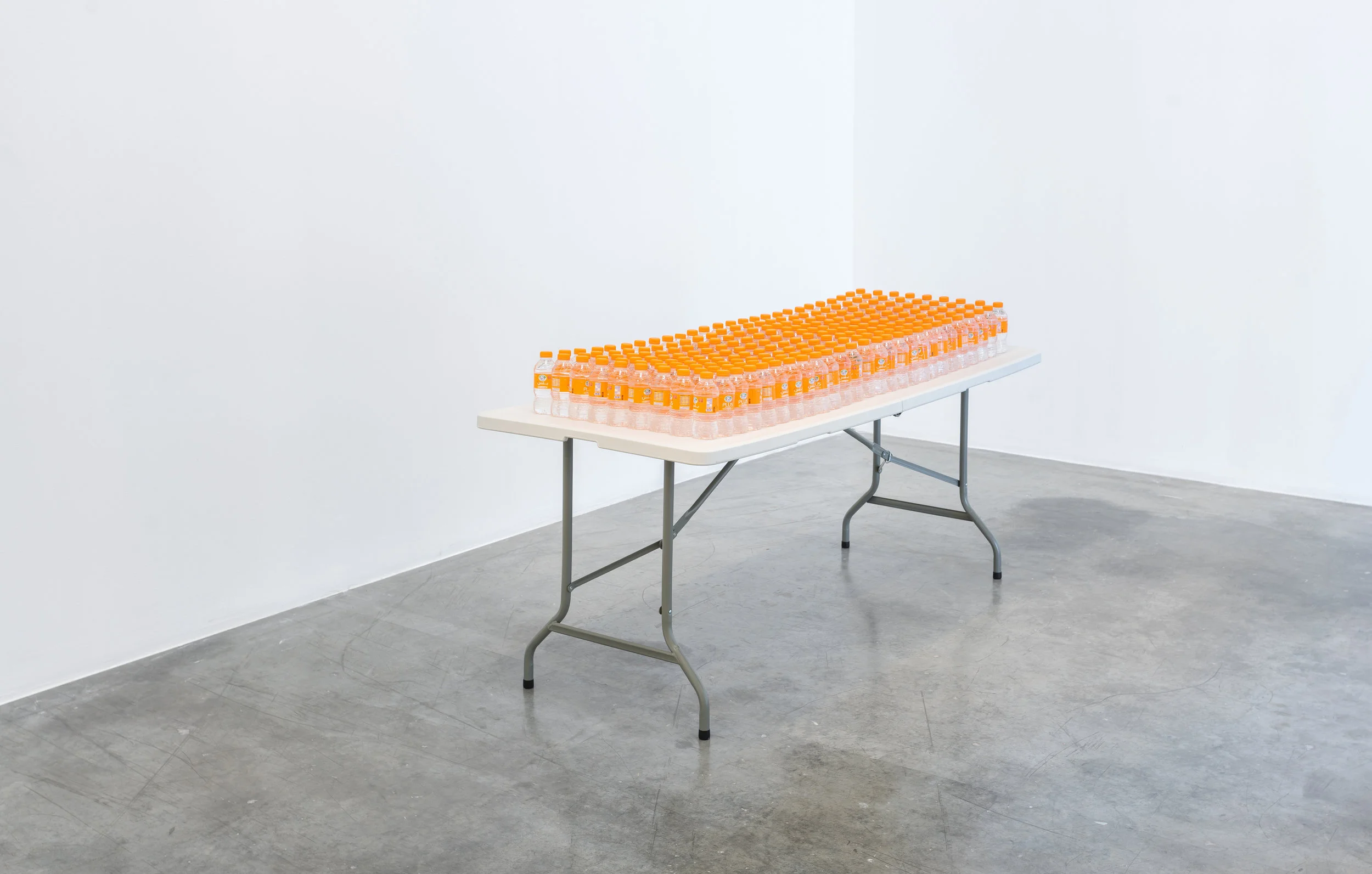 SUNSHINE, 2018, water bottles, table, Al Ain Vitamin D water bottles on a plastic folding table, dimensions variable. Image courtesy of the artist and Grey Noise.