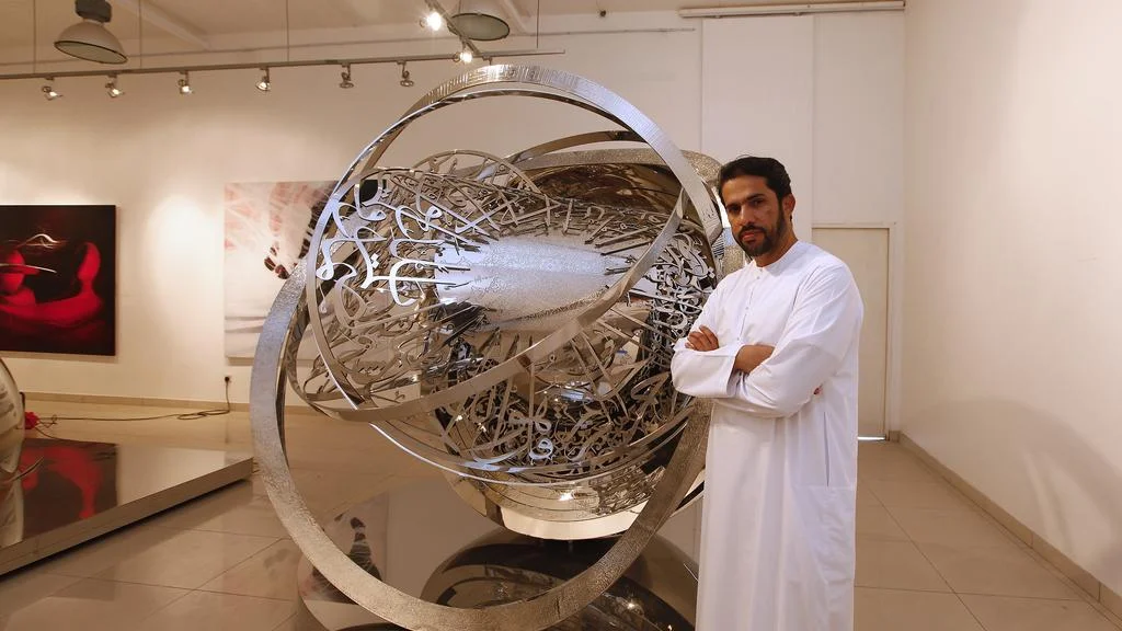 Mattar Bin Lahej stands next to one of his large sculptures made from calligraphic lettering and summarising his artistic practice focused on movement. Image courtesy of The National