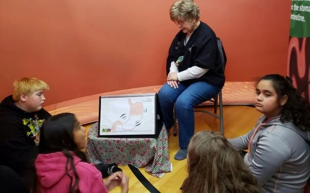 Food is swallowed through the esophagus and moves into the stomach. In this stomach station, Joyce Breadles-Fry teaches students about digestion. The stomach is like a stretchy bag that holds food after it is eaten. When the stomach is empty, it shrinks like a balloon without air. As you eat the stomach gets bigger & bigger. This station includes a sandwich-building activity that reinforces the important concept of choosing foods from MyPlate. The food then travels into the small intestines.