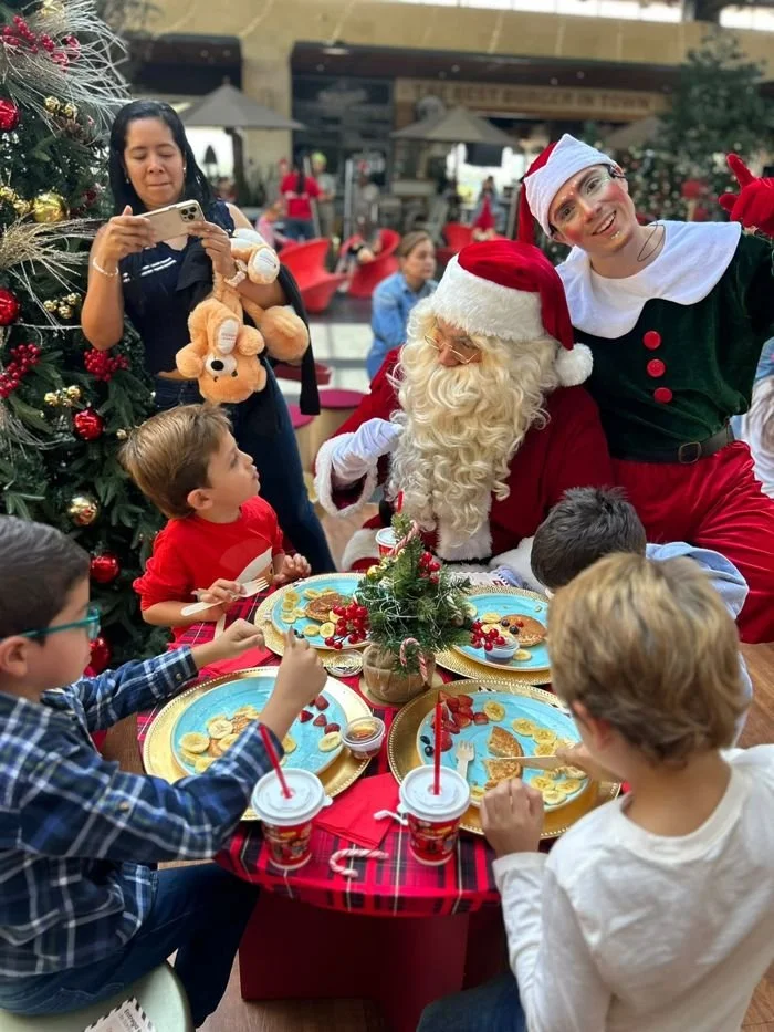 Niños desayunando con Santa y un duende en el centro comercial