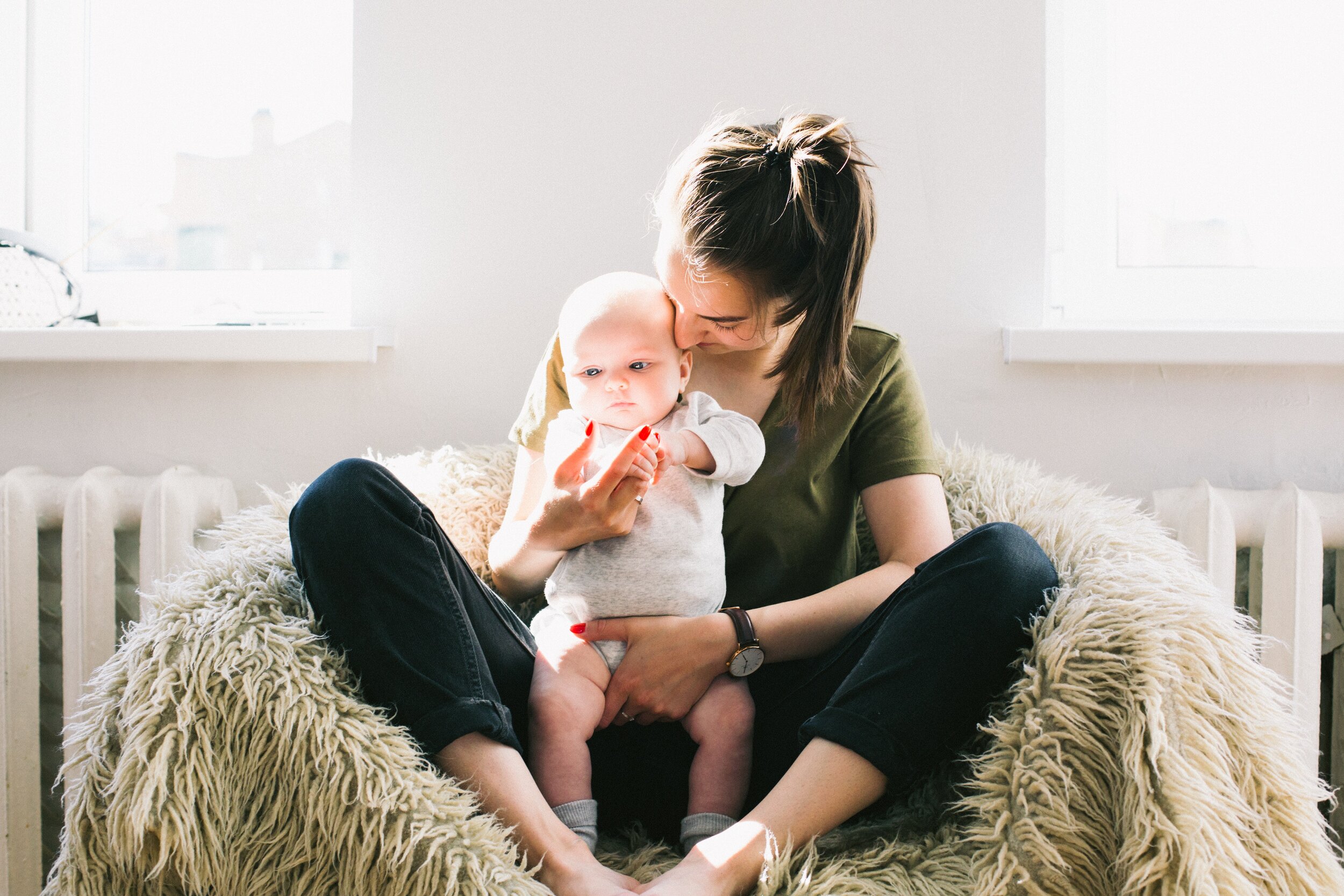 woman-holding-baby-while-sitting-on-fur-bean-bag-698878.jpg