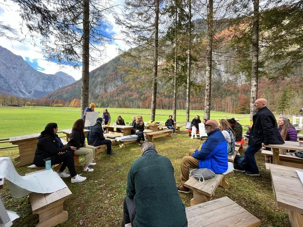outdoor workshop under pine trees, alpine valley, presenter with flip chart.jpeg