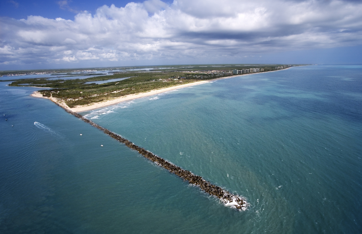 Aerial view of Fort Pierce Inlet and the Treasure Coast shoreline with blue water, beaches, and coastal neighborhoods.